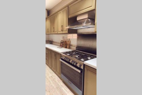a kitchen with wooden cabinets and a stove top oven at Luxury fully furnished villa ڤيلا مؤثثة in AlUla