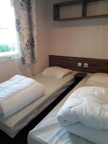 two twin beds in a room with a window at Mobilhome beaux volumes ES40 in Fréjus