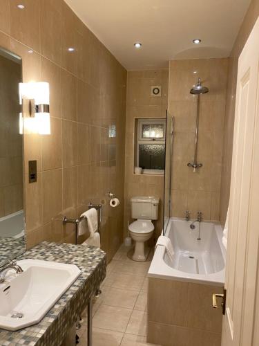 a bathroom with a tub and a toilet and a sink at The Elizabeth House Hotel in Southampton