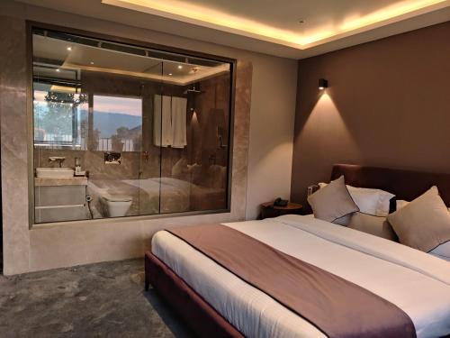 a bedroom with a large bed and a large window at Leela Resort in Mahabaleshwar