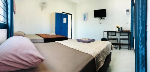 a hotel room with two beds and a television at บ้านนอกเมืองรีสอร์ต BaanNokMueang in Phayao