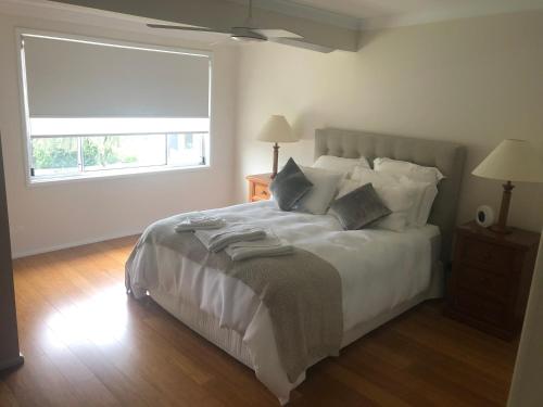 a bedroom with a large white bed with a window at House Beside The Lake in Summerland Point