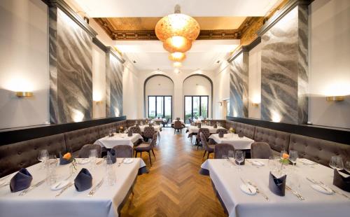 a restaurant with white tables and chairs and a chandelier at Hotel de France Wiesbaden City in Wiesbaden