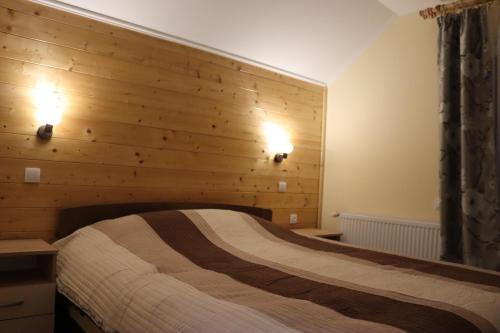 a bedroom with a wooden wall with a bed at Vila Zorica Vodice in Zlatibor
