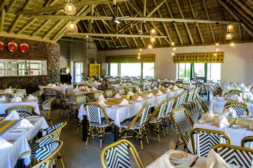 uma grande sala de jantar com mesas e cadeiras brancas em Cradle Moon Lakeside Game Lodge em Muldersdrift