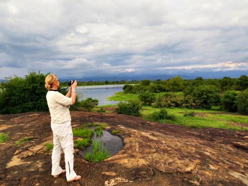 a woman taking a picture of a river at Mahoora Udawalawe - by Eco Team in Udawalawe