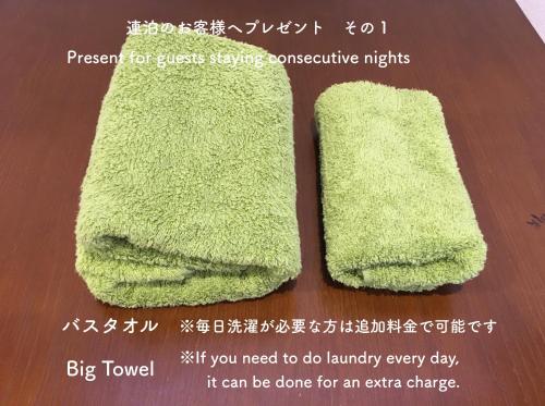 un cartel con dos toallas verdes en una mesa en Guesthouse Arakura en Fujiyoshida