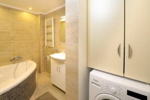 a bathroom with a sink and a washing machine at ORANGEHOMES two bedroom apartment Ráday str. in Budapest