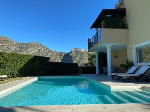 a swimming pool in front of a house with mountains at Villa Almond in Taormina
