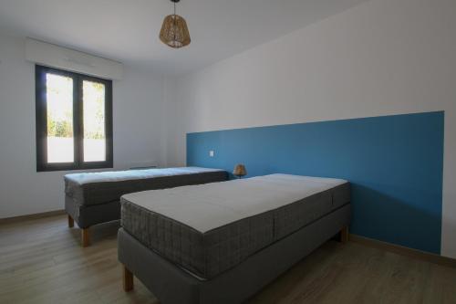 - une chambre avec 2 lits et un mur bleu dans l'établissement La Cabine du Moussaillon, à Saint-Gilles-Croix-de-Vie