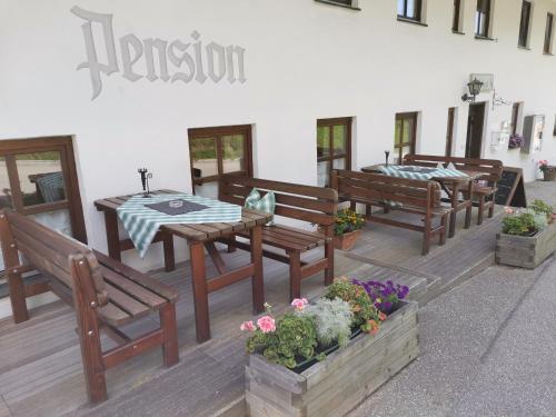 a patio with wooden benches and a table and flowers at Pension Nachtigall in Gottfrieding