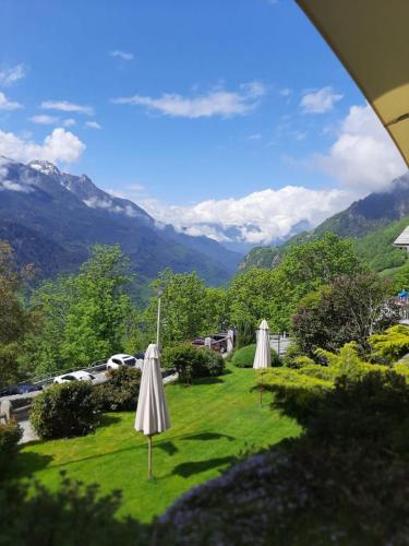 two white umbrellas on a lawn with mountains in the background at Hotel Stüa Granda in Soglio