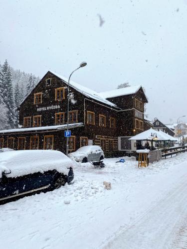 a building covered in snow with cars parked in front at Hotel Hvezda in Pec pod Sněžkou