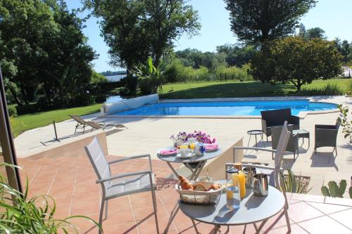 d'une terrasse avec une table et des chaises à côté de la piscine. dans l'établissement Clos Bernon, à Libourne