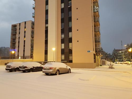 2 voitures garées sur un parking en face d'un immeuble dans l'établissement Heli apartment, à Tallinn
