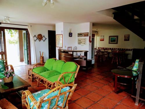 a living room with a green couch and chairs at Pousada Morada Da Prainha in Torres