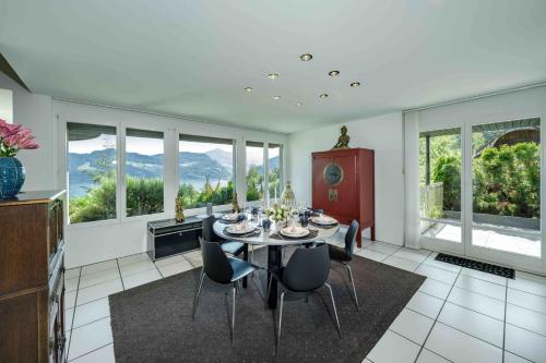 a dining room with a table and chairs and windows at Villa Ysara, Pool Villa with lake Lucerne View in Lucerne