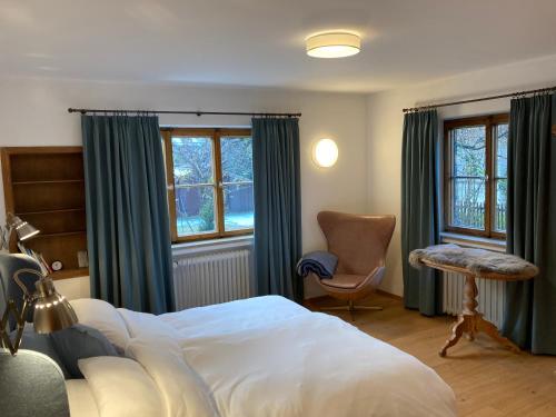 um quarto com uma cama, uma cadeira e janelas em Home Office und Ferienhaus Valentin in Oberammergau em Oberammergau