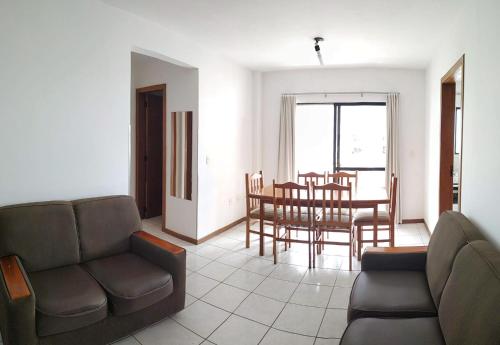 sala de estar con sofá, mesa y sillas en Residencial Chanel, en Balneário Camboriú
