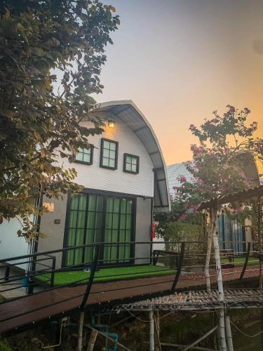 a house with green windows on the side of it at ข้าวทุ่งเบ็ญจาโฮมสเตย์ in Ban Hat Phang