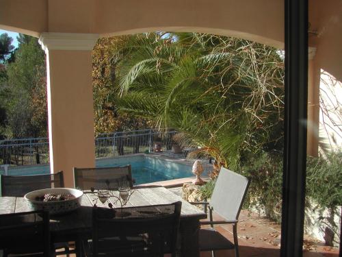 un patio avec une table et des chaises et une piscine dans l'établissement le patio, à Tourtour