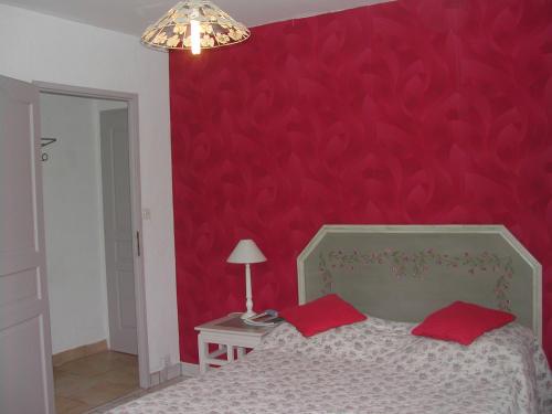 le patio في تورتور: غرفة نوم بجدار احمر وسرير بمخدات حمراء