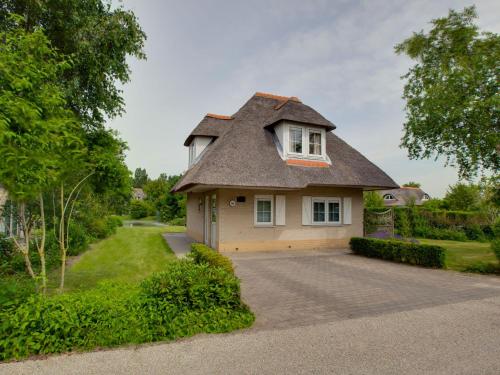 a house with a thatched roof with a driveway at Holiday Home Citta Romana-1 by Interhome in Hellevoetsluis