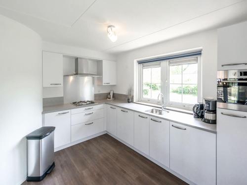 a white kitchen with white cabinets and a window at Holiday Home Citta Romana-1 by Interhome in Hellevoetsluis
