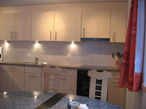 サースフェーにあるHoliday Home Haus Alpenstern- Wohnung Aelpi by Interhomeのキッチン(白いキャビネット、カウンタートップ付)