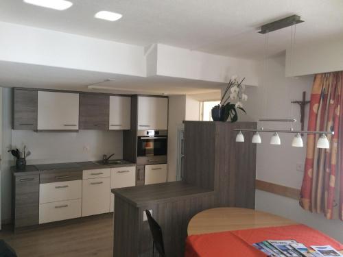 サースフェーにあるApartment Chalet Sunstar- kleine Wohnung by Interhomeの白いキャビネットとテーブル付きのキッチンが備わります。