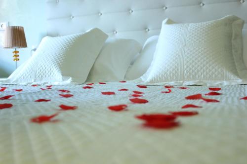 a white bed with red rose petals on it at Locanda Navona in Rome