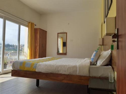 a bedroom with a bed and a large window at EDEN Paradisee in Ooty