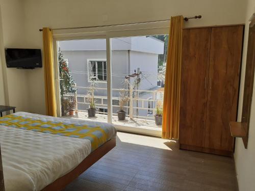a bedroom with a bed and a large glass window at EDEN Paradisee in Ooty