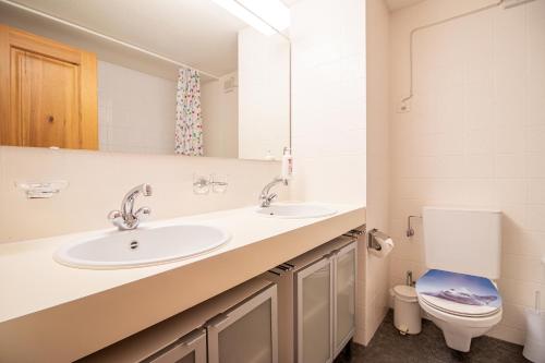 een badkamer met 2 wastafels en een toilet bij Rothornblick 57 by Arosa Holiday in Arosa