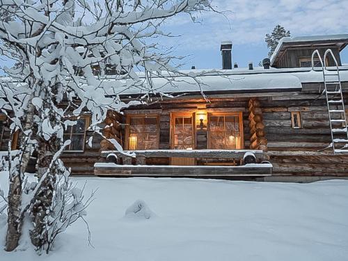 eine Blockhütte im Schnee mit eingeschaltetem Licht in der Unterkunft Holiday Home Ylläsniesta 5 e 12 by Interhome in Äkäslompolo