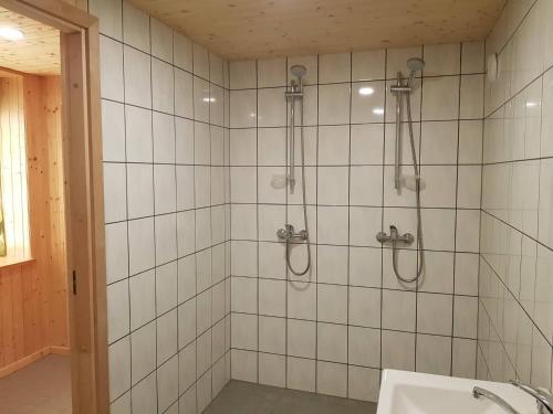 a shower in a bathroom with white tiles at Viirpuu puhkemaja in Kuressaare