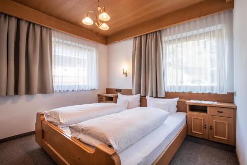 een slaapkamer met een groot bed en 2 ramen bij Gästehaus Appartement Höllwarth in Stumm