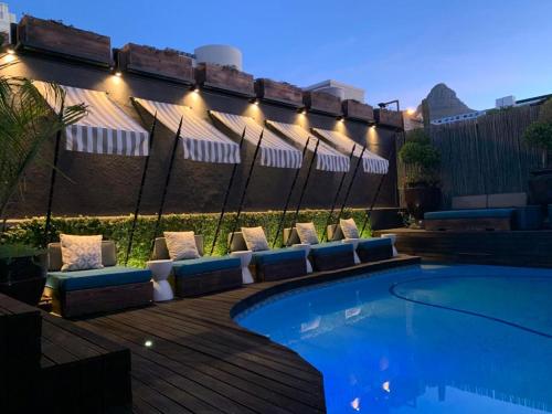 a swimming pool with lounge chairs and an umbrella at Mountview Guest House in Cape Town