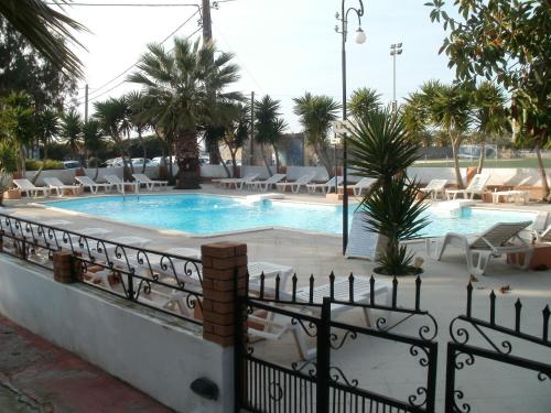 a swimming pool with chairs and a fence at Miranta Hotel - Apartments & Studios in Aegina Town
