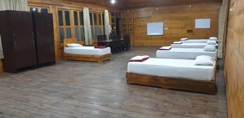 a row of beds in a room with wooden walls at Brushwood Villa- Cottages and Bar in Palolem