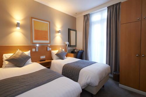 a hotel room with two beds and a window at Luna And Simone Hotel in London