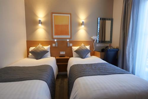 a hotel room with two beds and a mirror at Luna And Simone Hotel in London