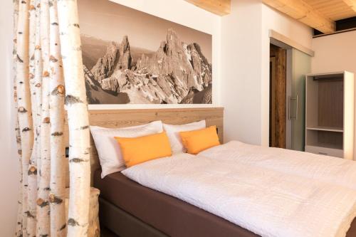 a bedroom with a bed with two orange pillows at Latemar Fiemme Apartments in Tesero