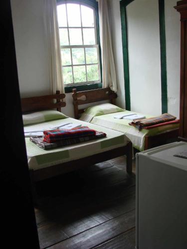 a small room with two beds and a window at Hotel Pousada Hospedaria Antiga in Ouro Preto