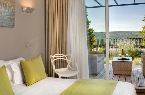 a bedroom with a bed and a balcony with a patio at Le Panoramic in Sancerre