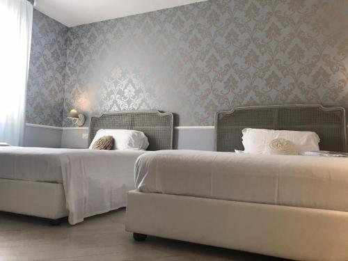 two beds in a hotel room with wallpaper at Marina Holiday & Spa in Balestrate