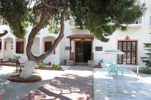 a patio with chairs and a tree in front of a building at Miranta Hotel - Apartments & Studios in Aegina Town