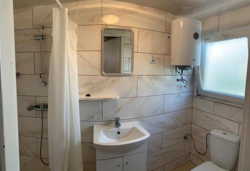 biała łazienka z umywalką i toaletą w obiekcie Domki Nad Jeziorem I Łabędź w Rajgrodzie