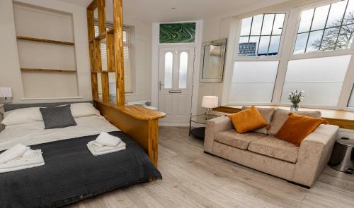 a bedroom with a bed and a couch and windows at Cosy Studio in Central Reading in Reading