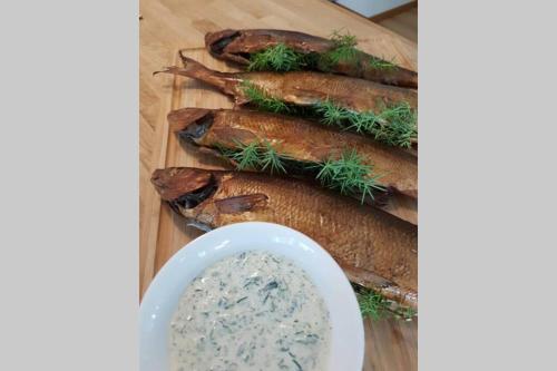 a bunch of fish on a cutting board with a dip at Guesthouse at Ingarö Stockholm archipelago (breakfast) in Grönskan